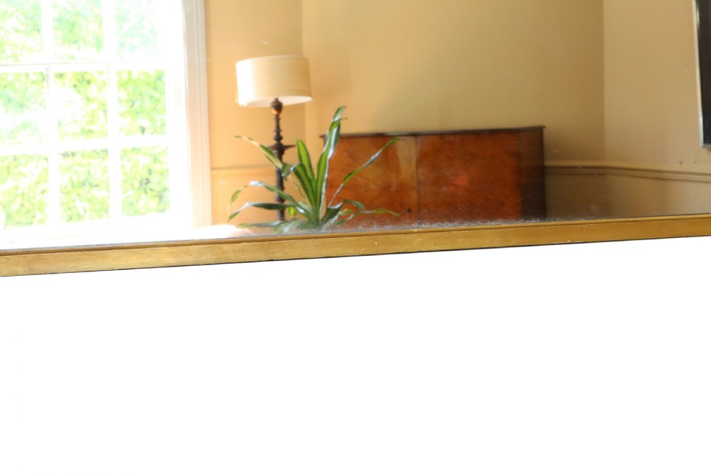 A large nineteenth-century arched giltwood overmantel mirror with subtle scroll mouldings along the lower frame. View VI