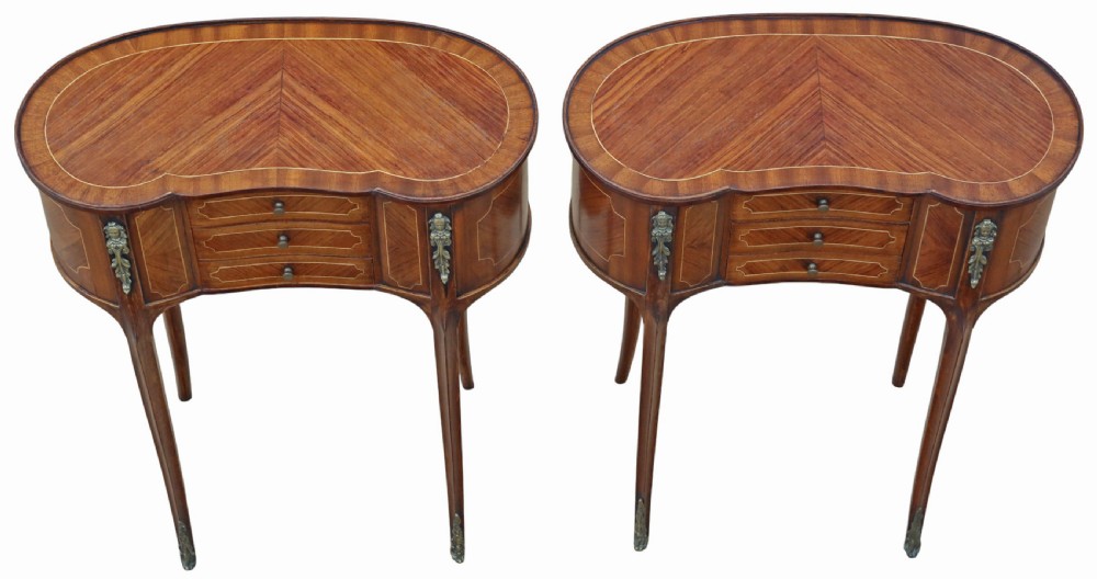 A pair of matching 1920s kidney-shaped timber bedside tables featuring inlaid veneering, central drawers, cabriole legs, and metal knee mounts.