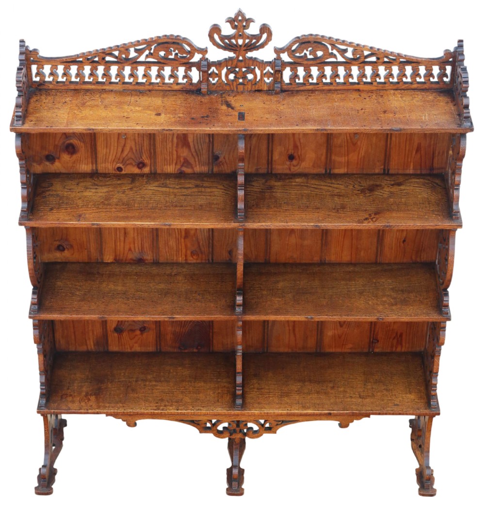 An antique brown oak waterfall bookcase featuring four graduated open shelves with intricate fret-cut scrollwork sides, central dividers, and a decorative cresting top. View II