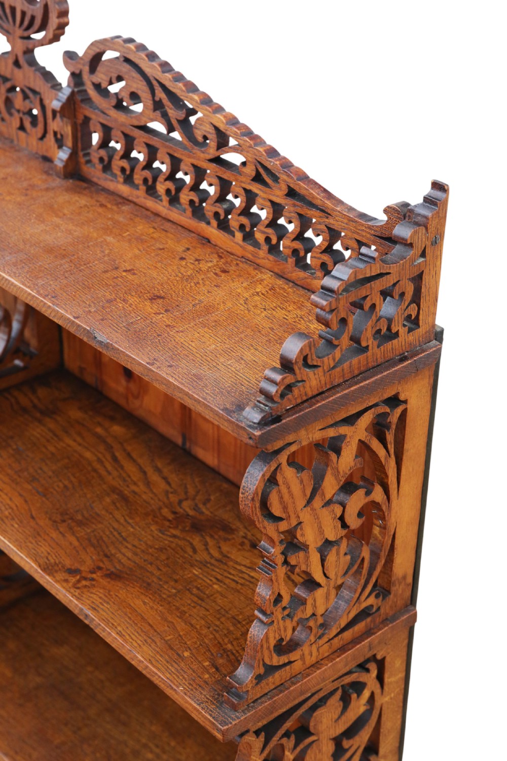 An antique brown oak waterfall bookcase featuring four graduated open shelves with intricate fret-cut scrollwork sides, central dividers, and a decorative cresting top. View V