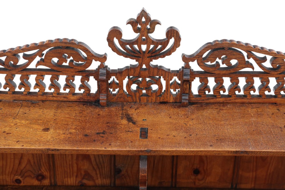 An antique brown oak waterfall bookcase featuring four graduated open shelves with intricate fret-cut scrollwork sides, central dividers, and a decorative cresting top. View VI