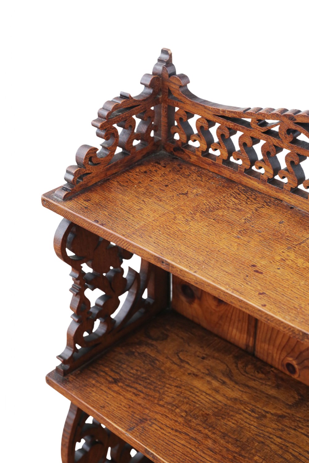 An antique brown oak waterfall bookcase featuring four graduated open shelves with intricate fret-cut scrollwork sides, central dividers, and a decorative cresting top. View VII