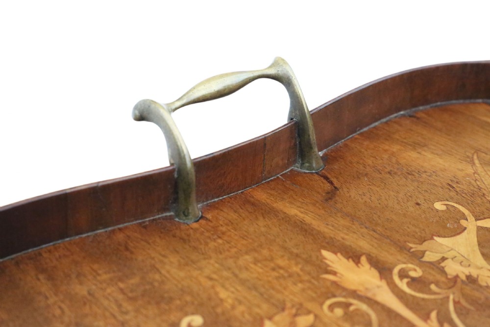 An Edwardian shaped mahogany serving tray featuring intricate marquetry inlay of cherubs and musical instruments with two brass handles. View V