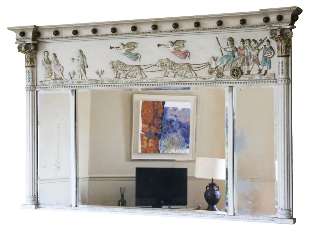 A 19th-century Regency overmantel mirror featuring an off-white painted frame with a classical chariot relief frieze above three mirror plates flanked by fluted pilasters. View II