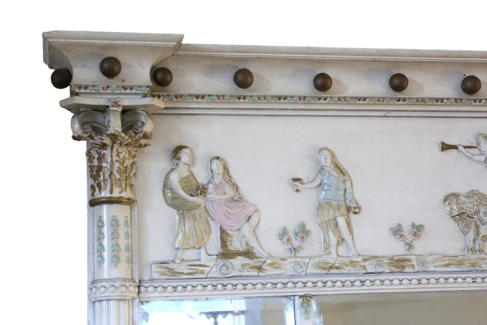 A 19th-century Regency overmantel mirror featuring an off-white painted frame with a classical chariot relief frieze above three mirror plates flanked by fluted pilasters. View III