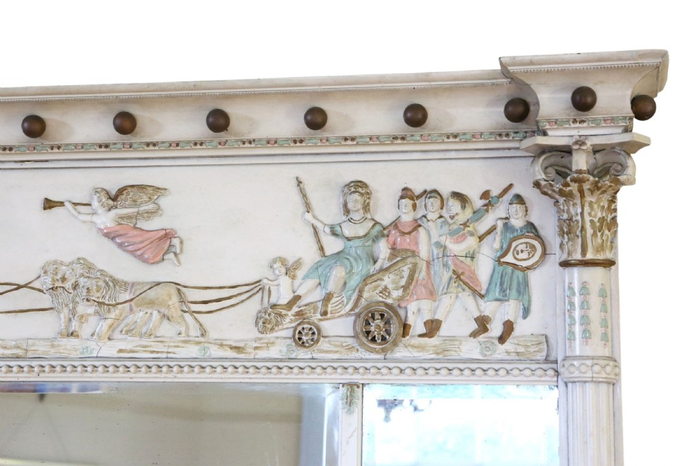 A 19th-century Regency overmantel mirror featuring an off-white painted frame with a classical chariot relief frieze above three mirror plates flanked by fluted pilasters. View V