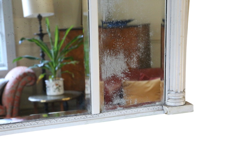 A 19th-century Regency overmantel mirror featuring an off-white painted frame with a classical chariot relief frieze above three mirror plates flanked by fluted pilasters. View VI