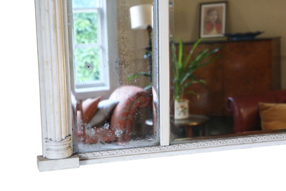 A 19th-century Regency overmantel mirror featuring an off-white painted frame with a classical chariot relief frieze above three mirror plates flanked by fluted pilasters. View VII