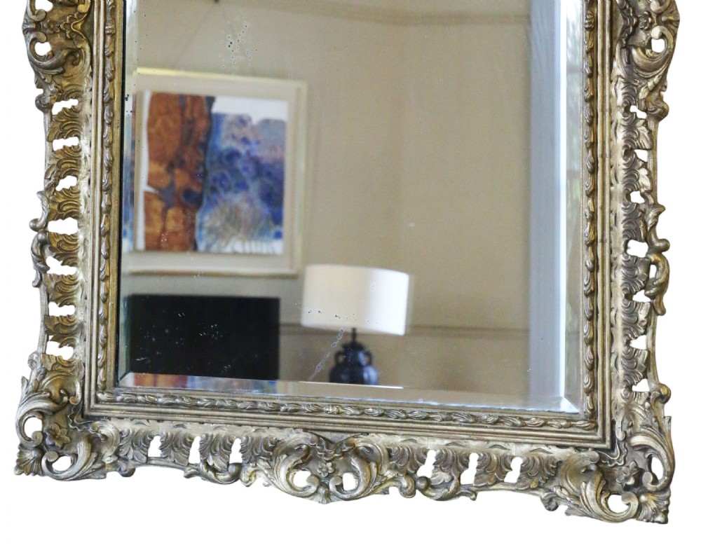 A rectangular 19th-century giltwood mirror featuring an ornate, openwork pierced frame carved with Rococo scrollwork and foliate details. View VIII