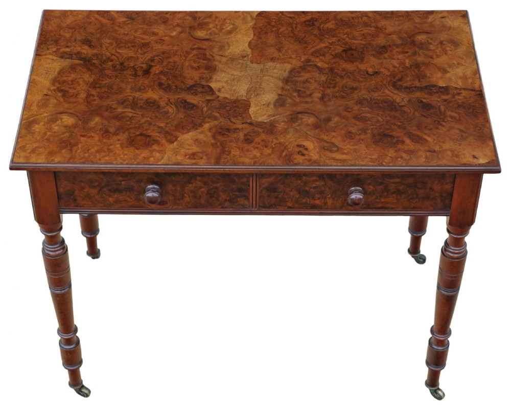 A nineteenth-century burr walnut writing table featuring a figured veneer top, two frieze drawers with turned wooden knobs, and tapering turned legs on brass castors. View III