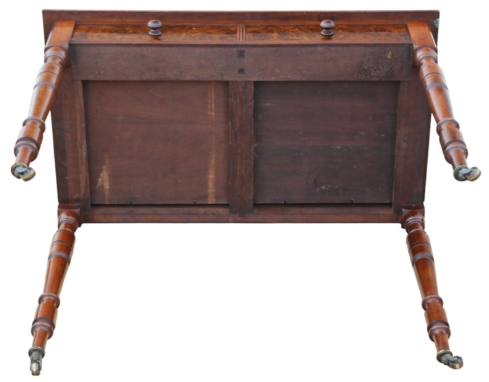 A nineteenth-century burr walnut writing table featuring a figured veneer top, two frieze drawers with turned wooden knobs, and tapering turned legs on brass castors. View VIII