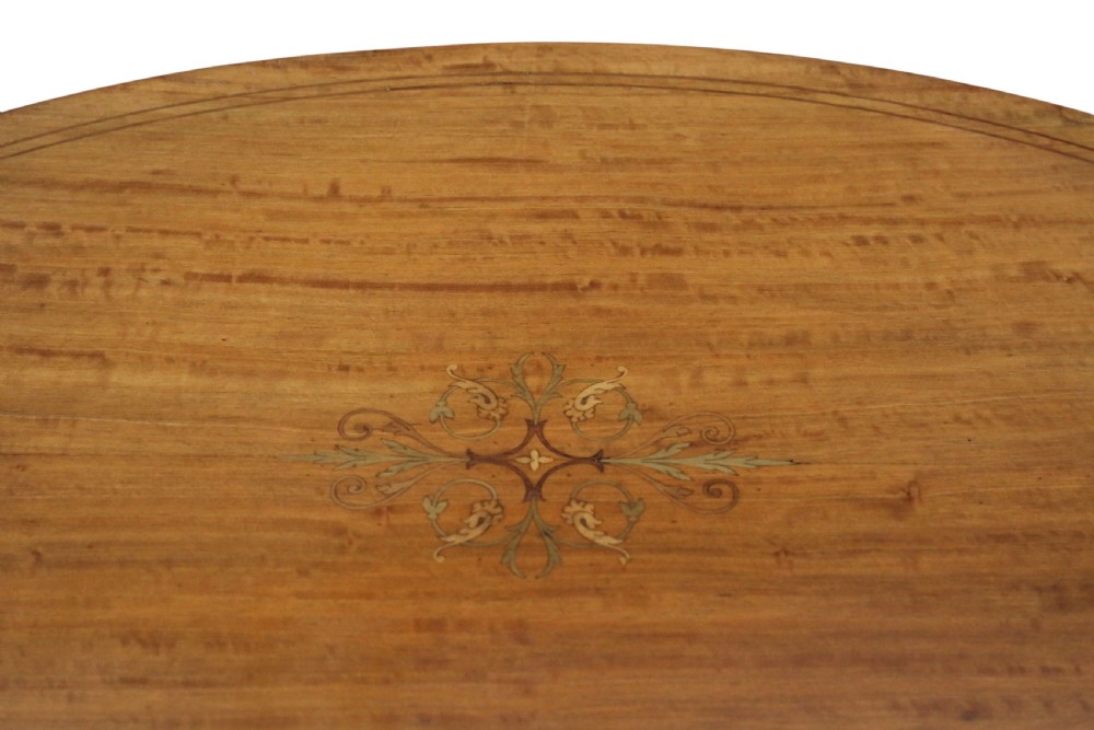 An oval Edwardian satin walnut occasional table with marquetry inlay on the top, slender tapered legs, and an oval undertier. View VI