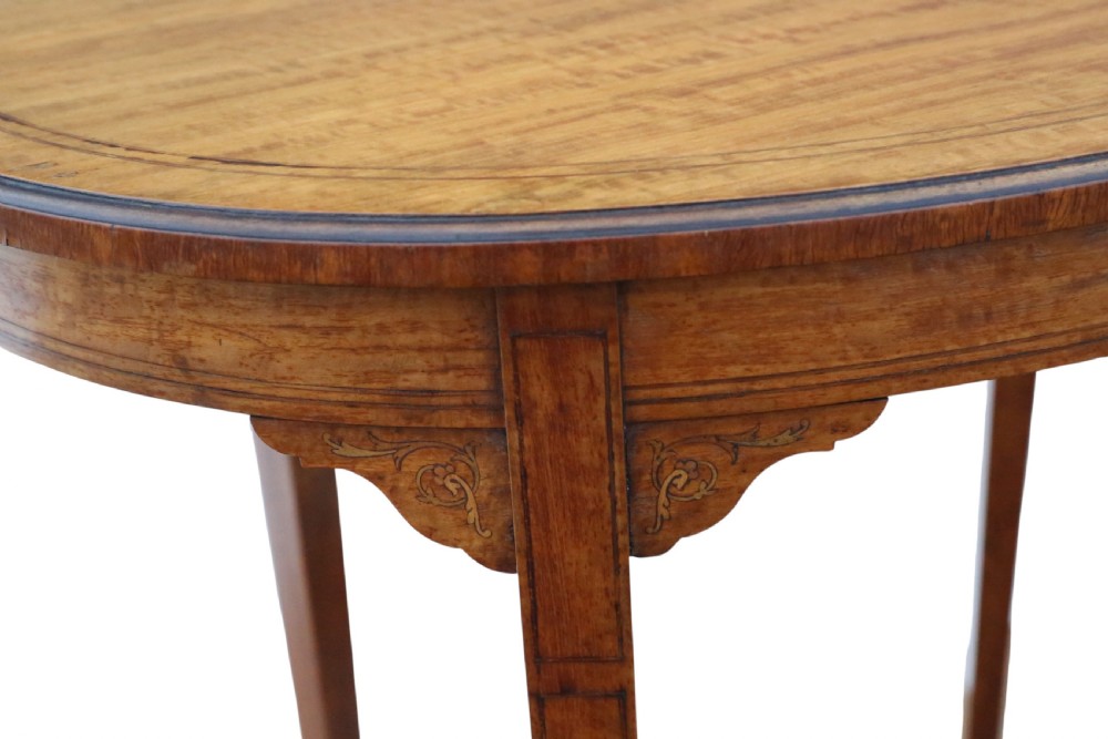 An oval Edwardian satin walnut occasional table with marquetry inlay on the top, slender tapered legs, and an oval undertier. View VIII