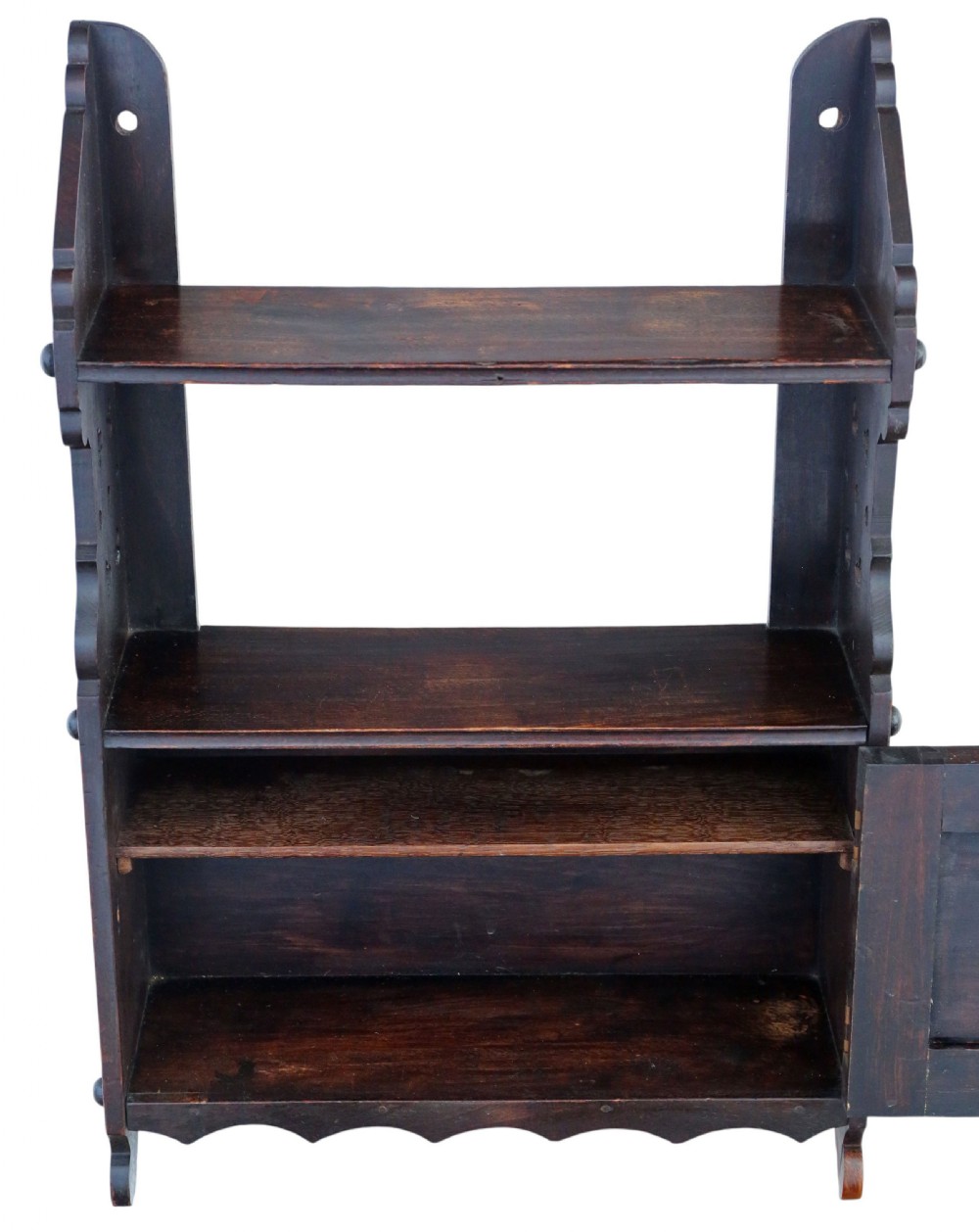 A dark brown Victorian Gothic carved oak wall shelf featuring open upper tiers, decorative side studs, cut-out patterns, and a carved lower cabinet door. View V