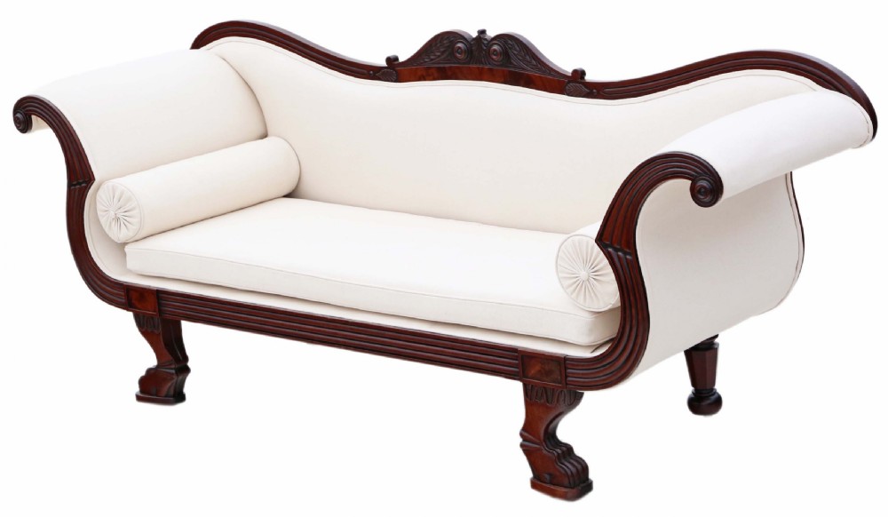 A 19th-century mahogany scroll arm sofa upholstered in neutral cream fabric with two matching bolster cushions and carved timber details.