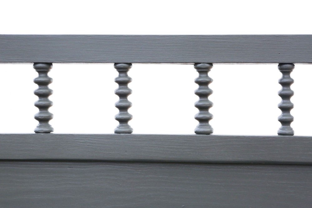 An antique grey painted wooden wall display shelf featuring a top gallery rail with turned spindles and shaped side brackets. View IV