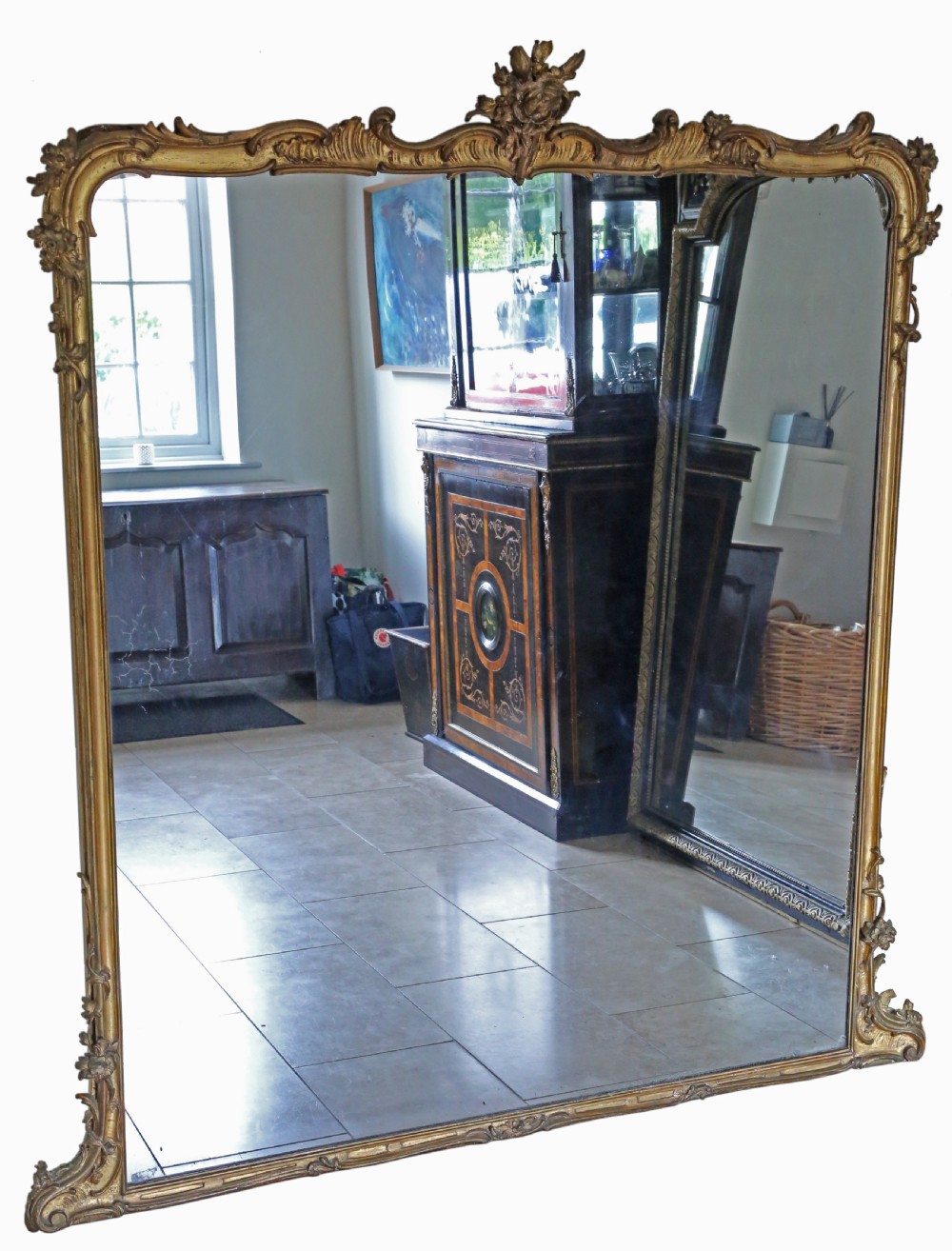 A large nineteenth-century giltwood overmantel mirror featuring an arched frame topped with a carved crest motif and lower foliage flourishes. View II
