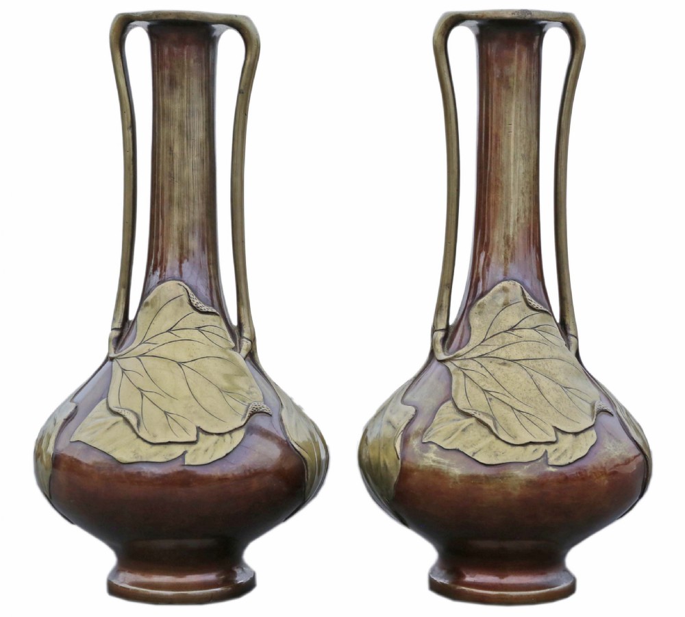 A pair of tall Japanese Meiji era mixed metal bronze vases featuring elongated necks, handles, and cast leaf relief details around the bulbous base. View II