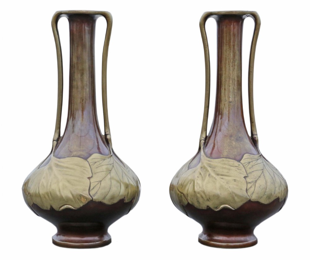 A pair of tall Japanese Meiji era mixed metal bronze vases featuring elongated necks, handles, and cast leaf relief details around the bulbous base. View VII
