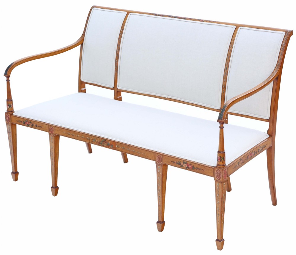 A late 19th-century painted satinwood sofa featuring cream fabric upholstery, three backrest panels, curved armrests, and hand-painted floral detailing on the timber frame. View II