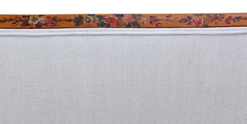 A late 19th-century painted satinwood sofa featuring cream fabric upholstery, three backrest panels, curved armrests, and hand-painted floral detailing on the timber frame. View VII