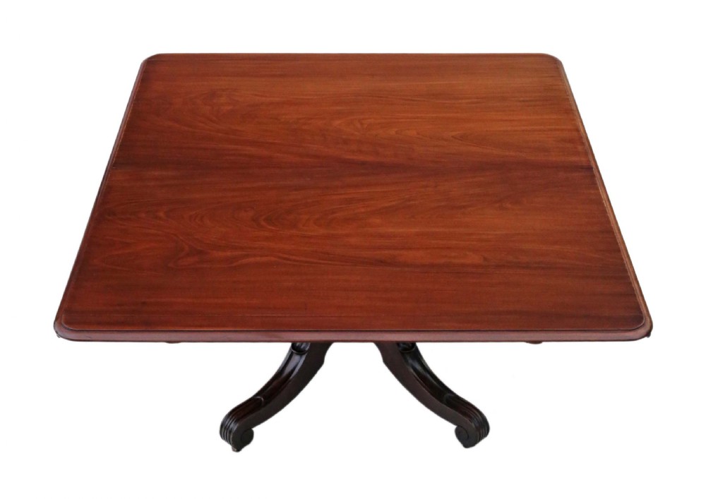 A 19th-century Regency Cuban mahogany dining table featuring a rectangular top with rounded corners supported by a central turned pedestal and four reeded splayed legs with brass castors. View II