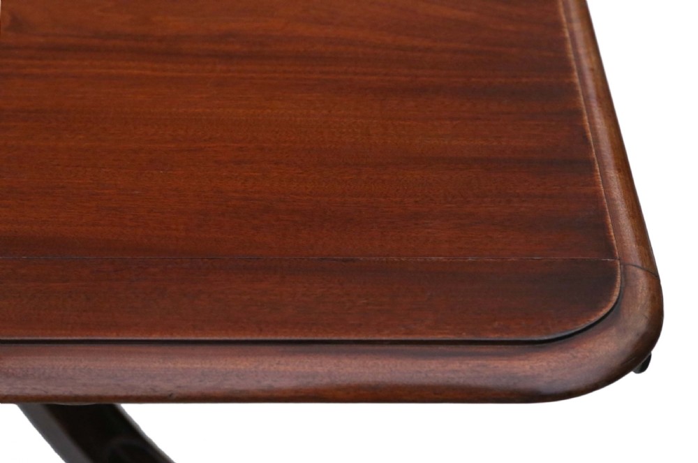 A 19th-century Regency Cuban mahogany dining table featuring a rectangular top with rounded corners supported by a central turned pedestal and four reeded splayed legs with brass castors. View IV
