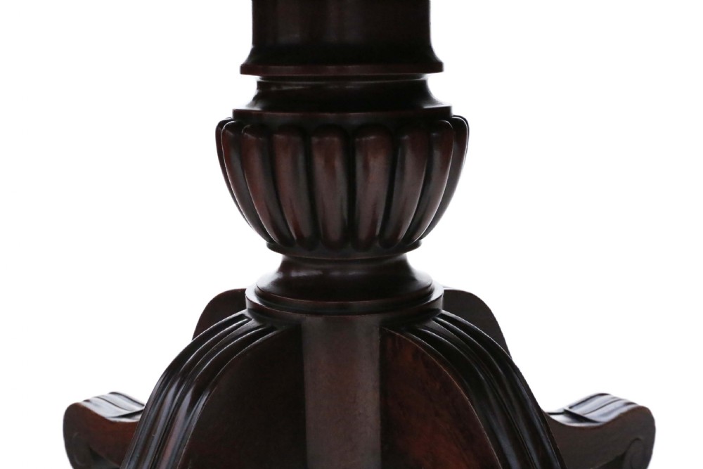 A 19th-century Regency Cuban mahogany dining table featuring a rectangular top with rounded corners supported by a central turned pedestal and four reeded splayed legs with brass castors. View V