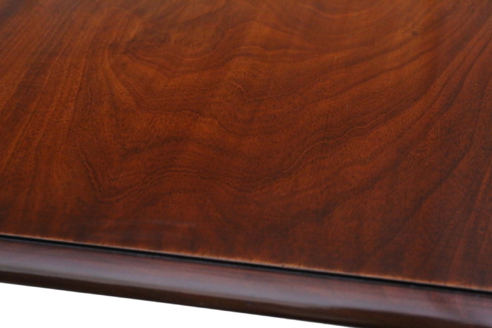 A 19th-century Regency Cuban mahogany dining table featuring a rectangular top with rounded corners supported by a central turned pedestal and four reeded splayed legs with brass castors. View VI
