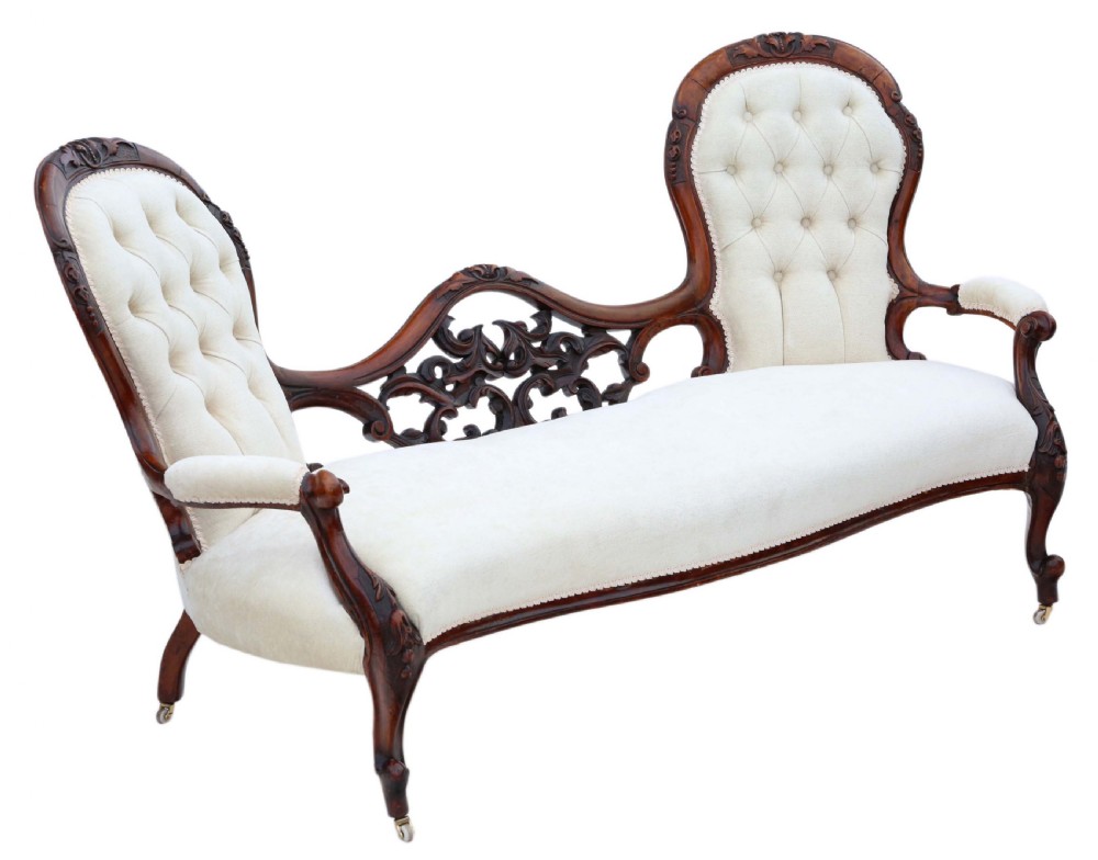 A mid-19th century Victorian carved walnut chaise longue with button-backed cream fabric upholstery, pierced floral backrest carving, and cabriole legs on castors.
