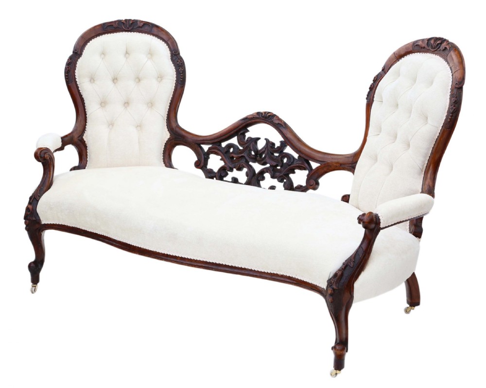 A mid-19th century Victorian carved walnut chaise longue with button-backed cream fabric upholstery, pierced floral backrest carving, and cabriole legs on castors. View VI