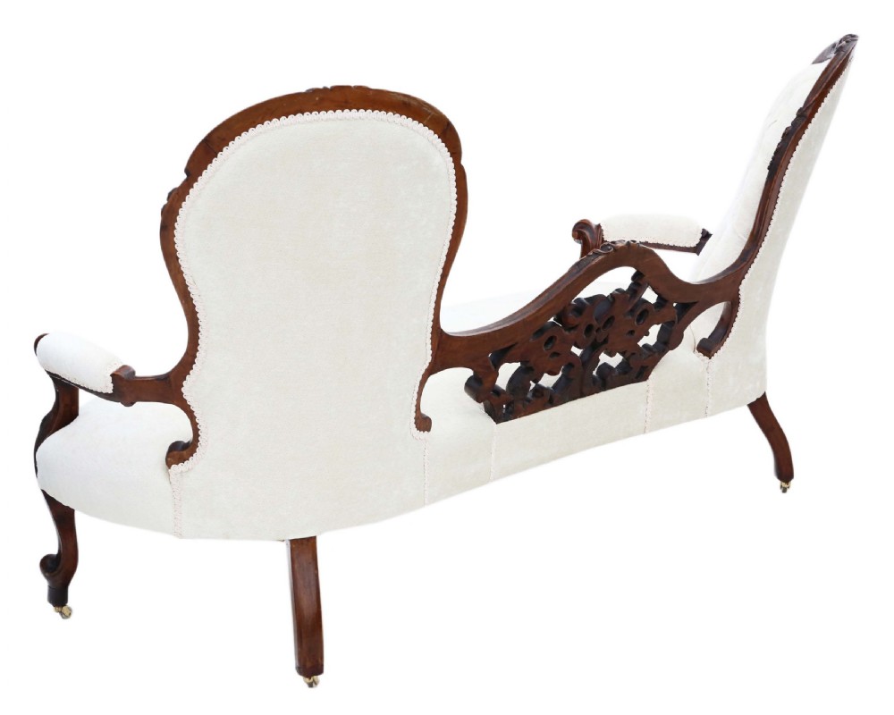 A mid-19th century Victorian carved walnut chaise longue with button-backed cream fabric upholstery, pierced floral backrest carving, and cabriole legs on castors. View VII