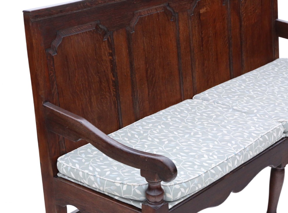 An 18th-century Georgian dark oak settle bench with a high fielded-panel back, shaped apron, turned front legs, and a light-coloured floral cushion. View III
