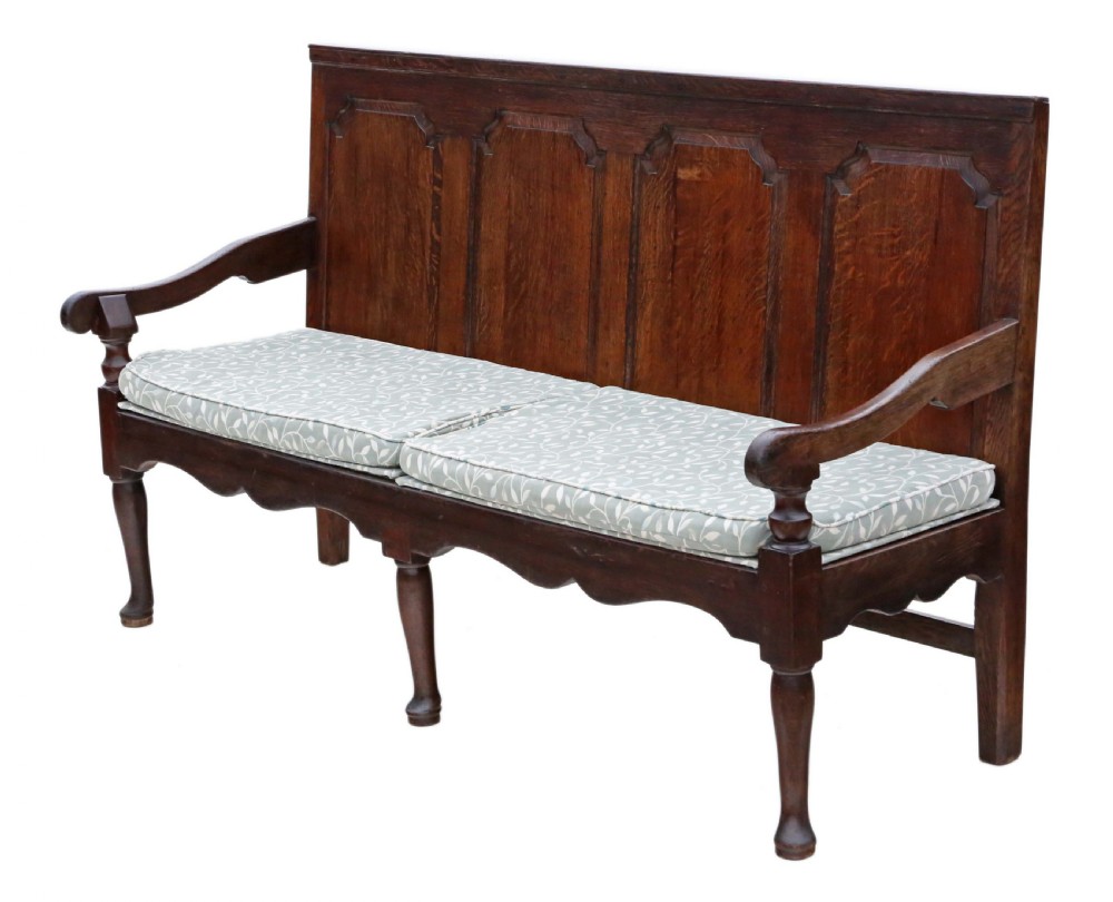 An 18th-century Georgian dark oak settle bench with a high fielded-panel back, shaped apron, turned front legs, and a light-coloured floral cushion. View IV