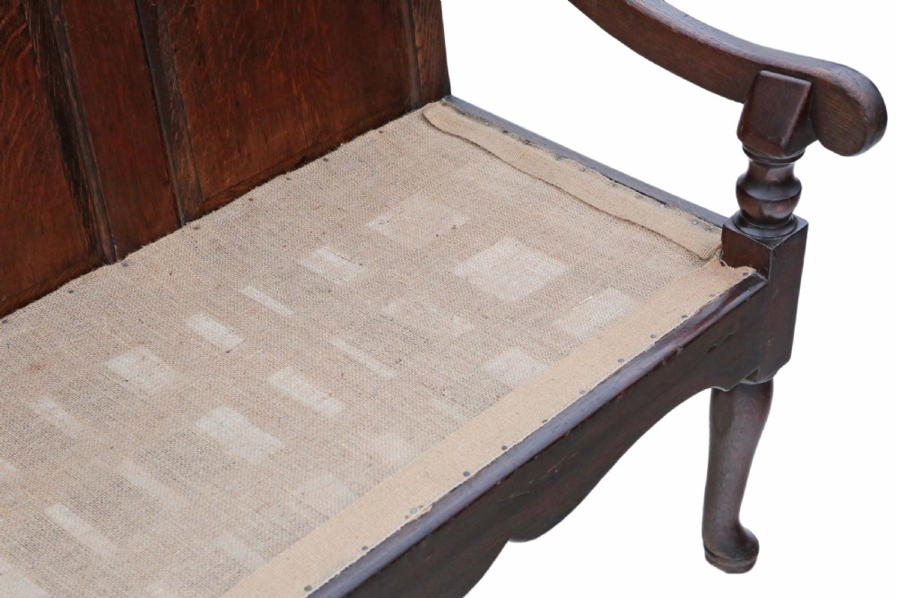 An 18th-century Georgian dark oak settle bench with a high fielded-panel back, shaped apron, turned front legs, and a light-coloured floral cushion. View VII