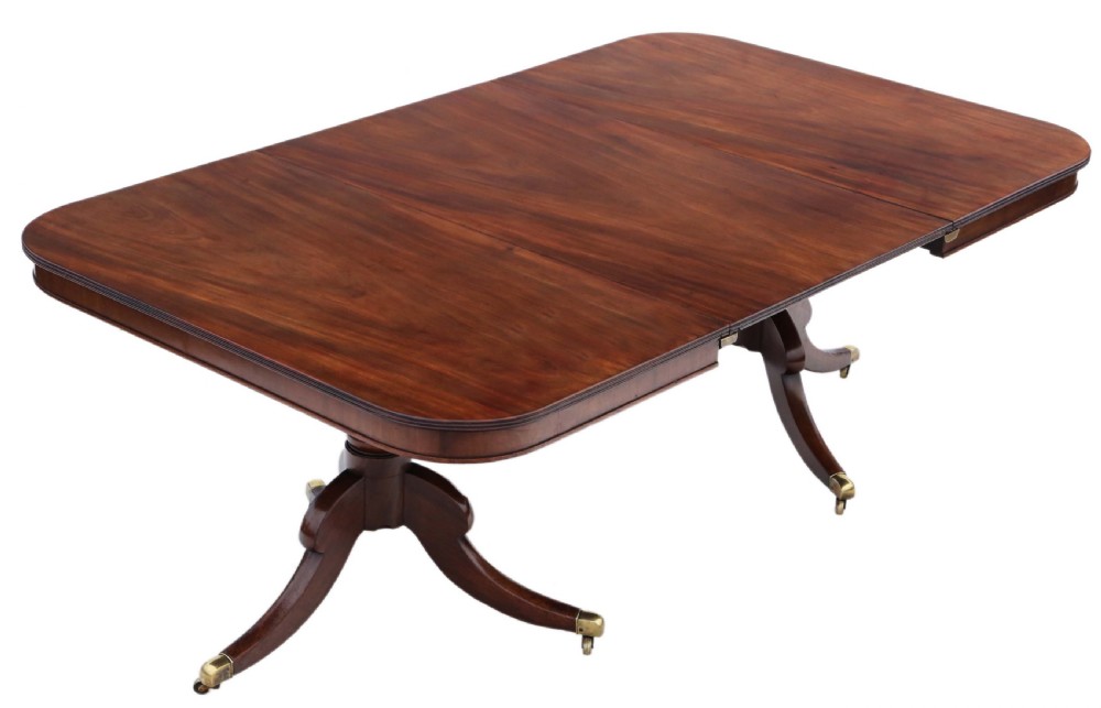 An early 19th century mahogany extending dining table with two pedestal bases, splayed legs, and brass castors.