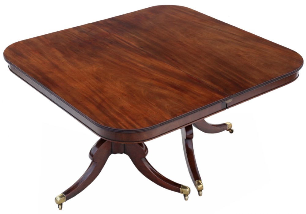 An early 19th century mahogany extending dining table with two pedestal bases, splayed legs, and brass castors. View X