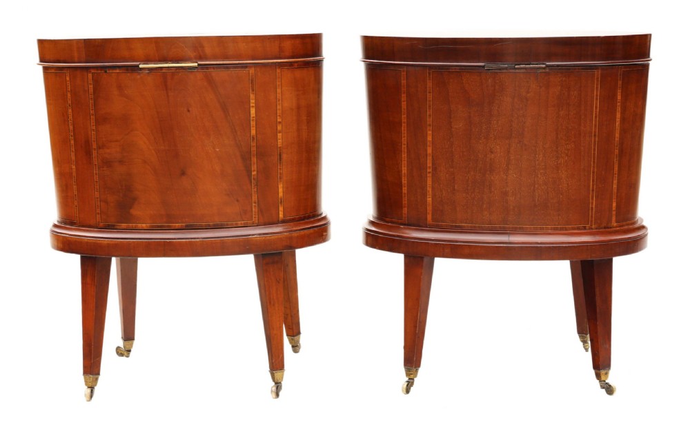 A pair of 19th-century oval mahogany cellarettes with line inlay, escutcheons, tapered legs, and brass castors. View V