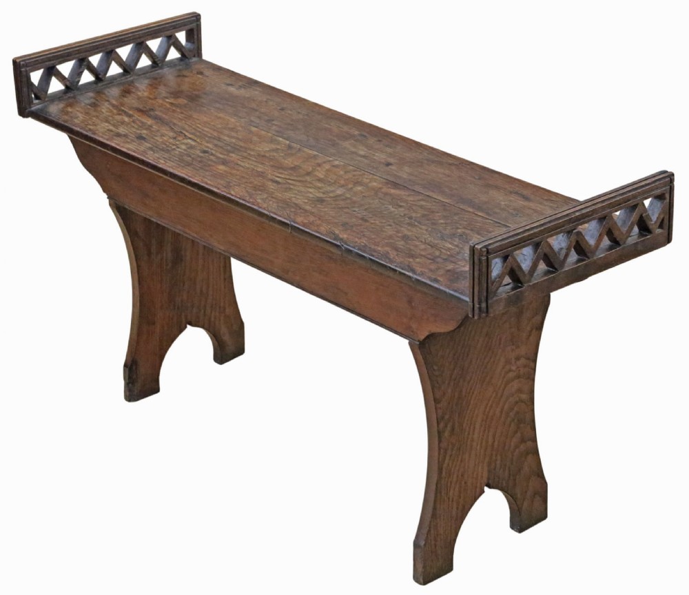 A 19th-century Arts and Crafts oak and elm window seat with pierced geometric gallery ends and solid shaped legs.