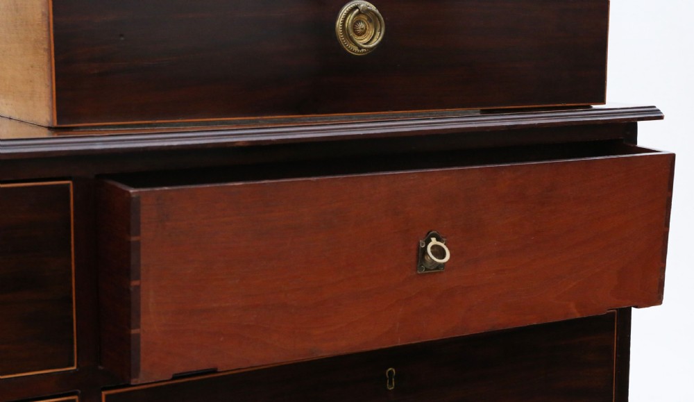 A 19th-century dark mahogany chest of drawers with decorative string inlay, brass ring handles, and a solid plinth base. View V