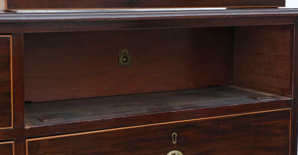A 19th-century dark mahogany chest of drawers with decorative string inlay, brass ring handles, and a solid plinth base. View VI