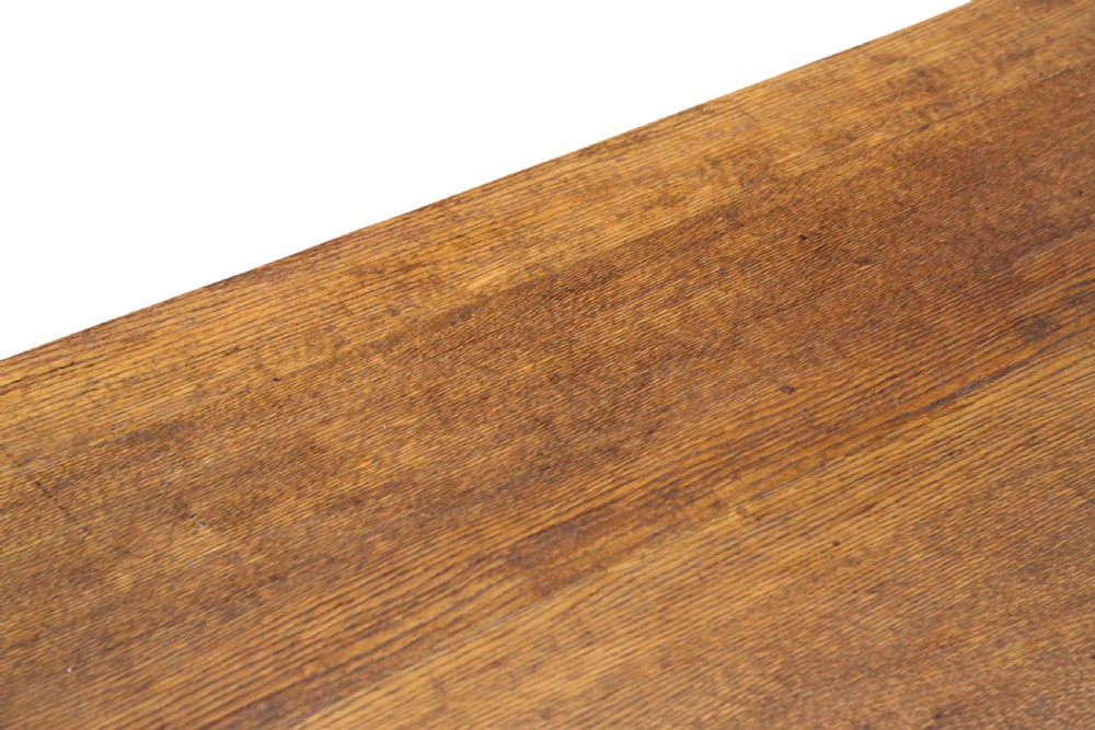 An antique late 19th-century solid oak Arts and Crafts refectory dining table featuring shaped trestle ends and a tusked tenon stretcher. View III