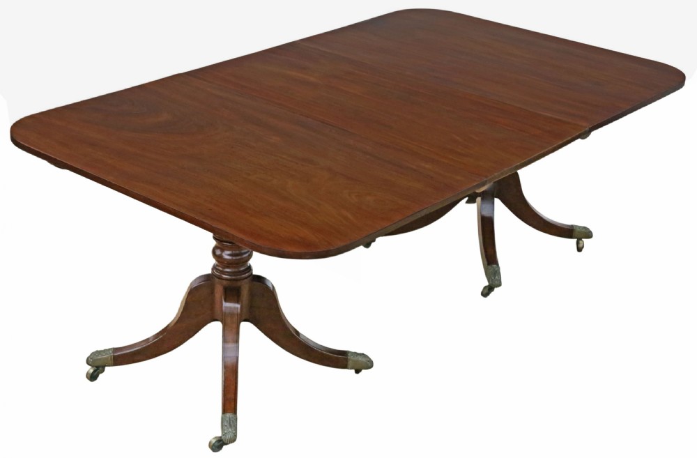 A 19th-century Georgian mahogany extending dining table set on twin pedestals with splayed legs and brass castors.