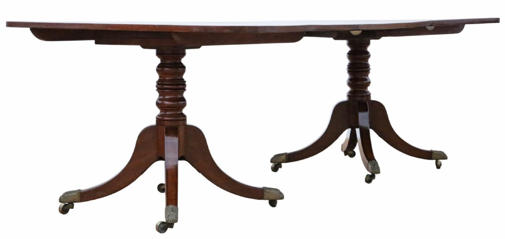A 19th-century Georgian mahogany extending dining table set on twin pedestals with splayed legs and brass castors. View II