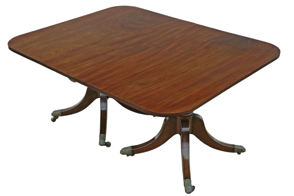 A 19th-century Georgian mahogany extending dining table set on twin pedestals with splayed legs and brass castors. View IX