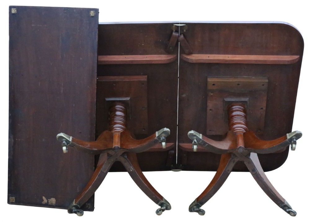 A 19th-century Georgian mahogany extending dining table set on twin pedestals with splayed legs and brass castors. View X