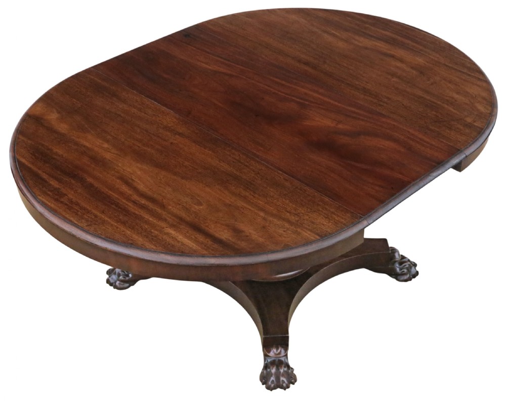 An antique nineteenth-century dark mahogany extending dining table featuring an oval top set on a central pedestal base with four carved paw feet. View II