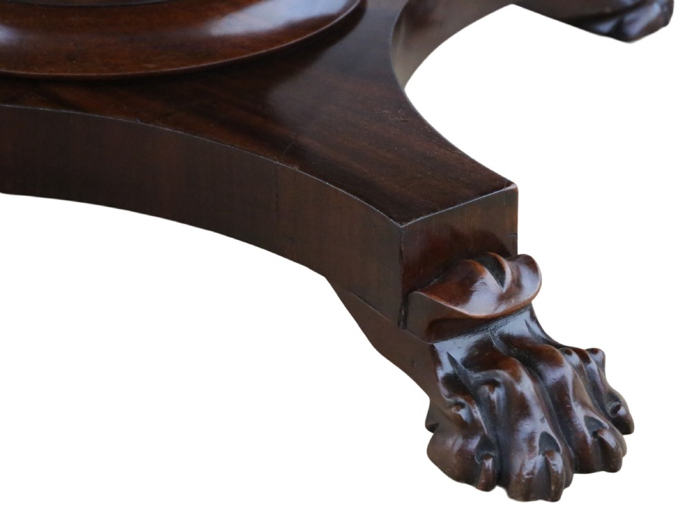 An antique nineteenth-century dark mahogany extending dining table featuring an oval top set on a central pedestal base with four carved paw feet. View IV