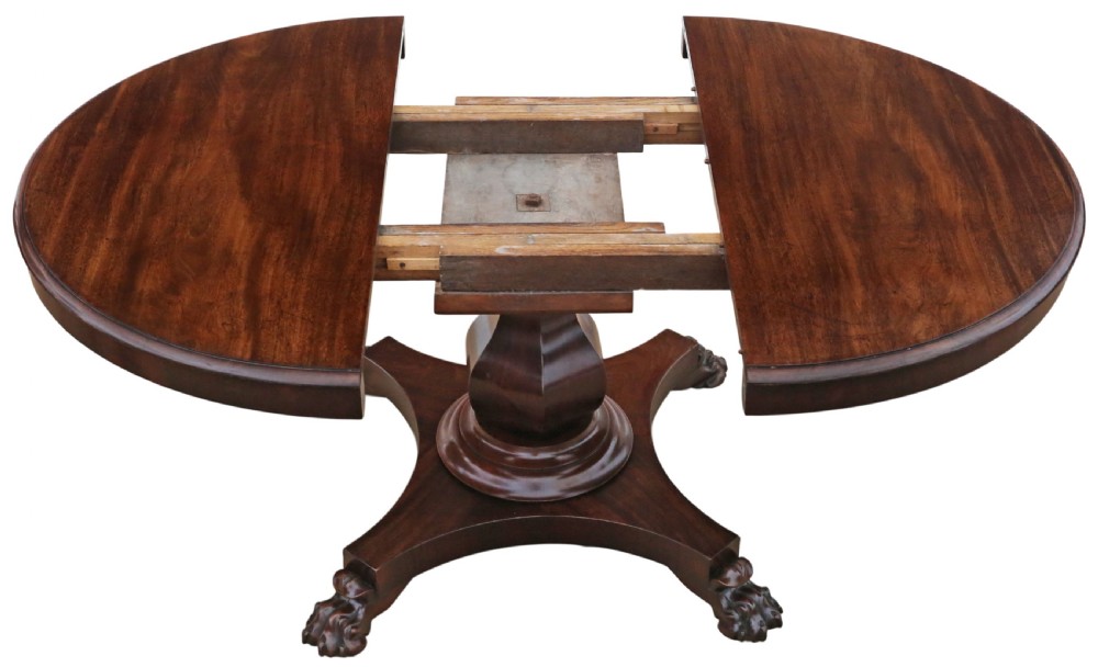 An antique nineteenth-century dark mahogany extending dining table featuring an oval top set on a central pedestal base with four carved paw feet. View VIII