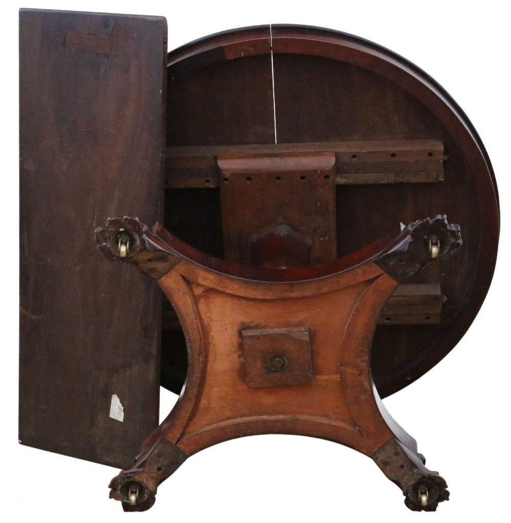 An antique nineteenth-century dark mahogany extending dining table featuring an oval top set on a central pedestal base with four carved paw feet. View IX